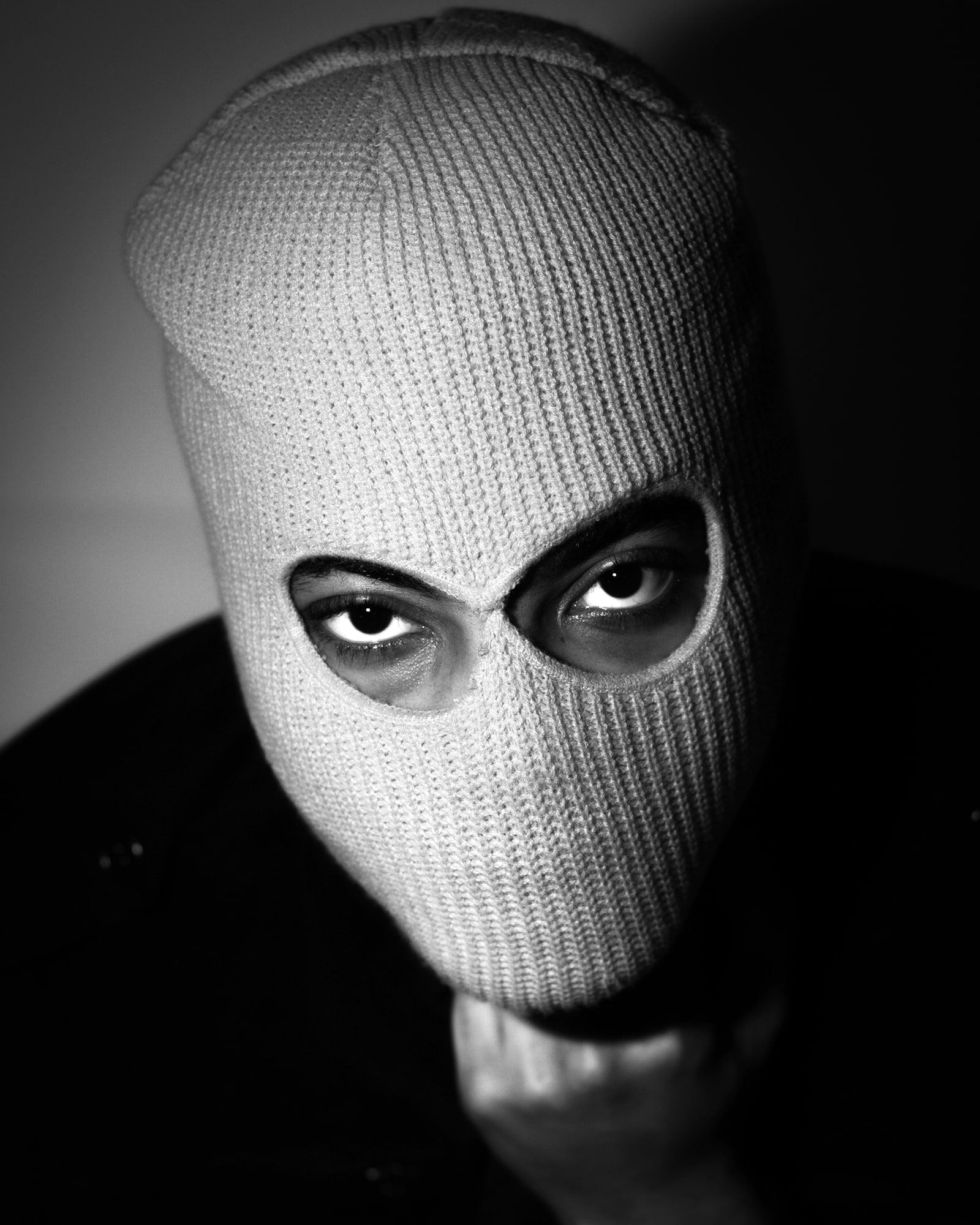 Black and white self-portrait in a knitted balaclava, eyes visible through the opening.